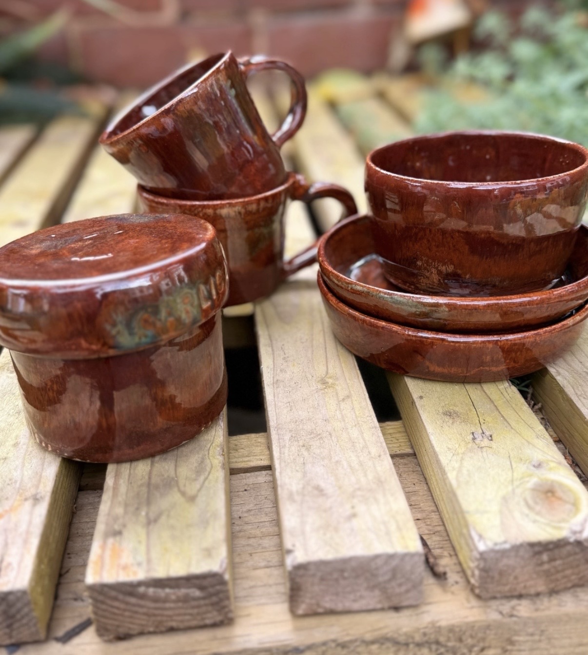 A playful family of handmade rust-glazed mugs, bowls and pots